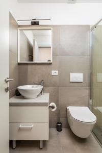 een badkamer met een wastafel, een toilet en een spiegel bij Apartments Penkala 2 in Rijeka