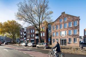 een vrouw die op een fiets door een straat rijdt bij City Trip Hostels Amsterdam-Purmerend in Purmerend