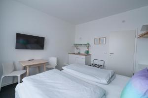 a bedroom with a bed, desk, and a television at BIG MAMA Leipzig in Leipzig