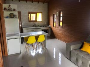 a kitchen with two yellow bar stools and a counter at Casa em Ibiraquera próxima a praia do Rosa in Imbituba