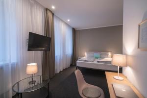 ein Hotelzimmer mit einem Bett und einem TV in der Unterkunft BIG MAMA Leipzig in Leipzig