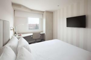 a bedroom with a white bed and a television at NH Barajas Airport in Madrid