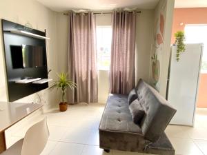 uma sala de estar com um sofá e uma televisão em Hotel APART Zuccolotto 201 em Aracruz