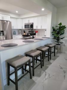 a kitchen with four stools and a counter with a counter top at FMB White Sands Retreat! in Fort Myers Beach