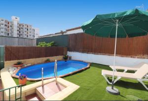 a green umbrella and a chair and a swimming pool at Apartamentos Nerjaplaya in Nerja