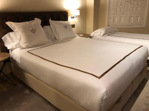 2 camas en una habitación de hotel con sábanas y almohadas blancas en Hotel Boutique Casa del Comendador en Navalcarnero