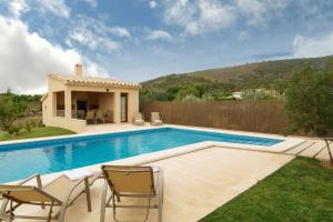 a swimming pool with chairs and a house at Carrusillo in Lloseta