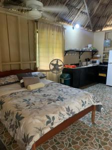 a bedroom with a large bed with a kitchen at Heavens Gate Beach Bungalows in Placencia