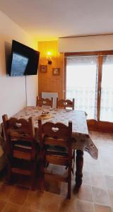 a dining room with a table and chairs and a television at Le coeur des Memises in Thollon