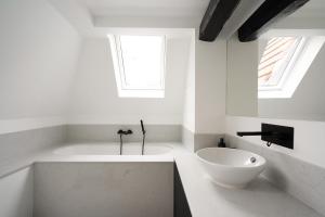 Baño blanco con bañera y lavamanos en Smartflats - Grand-Place II, en Bruselas