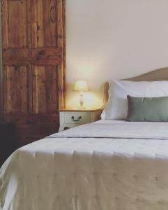a bedroom with a white bed with a wooden door at Vento d’Orcia in Pienza