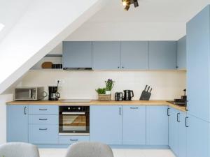 a white kitchen with blue cabinets and appliances at Vivando - Cosy Double Studio B + parking in Bucharest