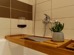 a glass of wine on a wooden tray with a plant at Vivando - Cosy Double Studio B + parking in Bucharest