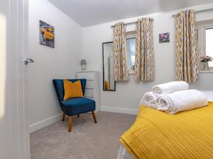 a bedroom with a yellow bed and a blue chair at Pass The Keys Stylish brand new two bedroom house, close to town in Ludlow