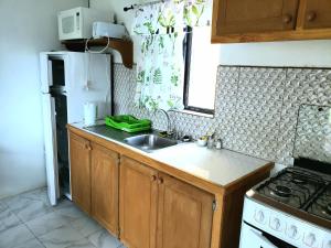 una pequeña cocina con fregadero y nevera. en Bay View Studio Apartment 3B - Canouan Island en Canouan
