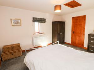 1 dormitorio con cama blanca y puerta de madera en Blackburn Cottage Barn, en Hamsterley