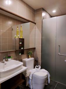 een badkamer met een wastafel, een toilet en een spiegel bij Maxine Suites in Kuala Lumpur
