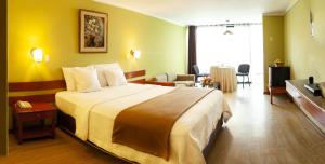 um quarto de hotel com uma cama grande e uma sala de estar em Holiday Suites em Tacna