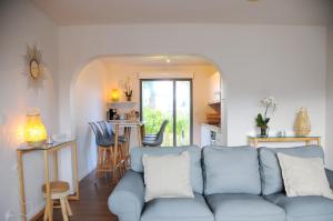 ein Wohnzimmer mit einem blauen Sofa und einer Küche in der Unterkunft Villa Jules Grand Gîte in Agon Coutainville