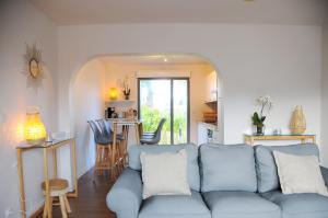 a living room with a blue couch and a kitchen at Villa Jules Grand Gîte in Agon Coutainville