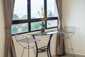 a table and two chairs in front of a window at Sri Sayang Seaview Holiday Home in Batu Ferringhi