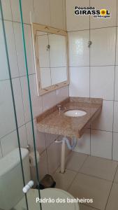 a bathroom with a sink and a mirror and a toilet at Pousada Girassol da Ferrugem in Garopaba