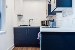 a kitchen with blue cabinets and a sink at Queen Street Apartments by Sasco in Blackpool