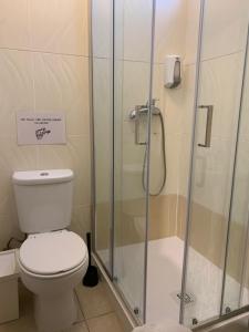uma casa de banho com um WC e uma cabina de duche em vidro. em Meeting Hostel em Figueira da Foz
