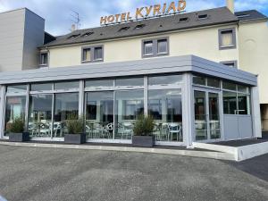 um hotel kyrkan com mesas e cadeiras num parque de estacionamento em Kyriad Le Mans Est em Le Mans