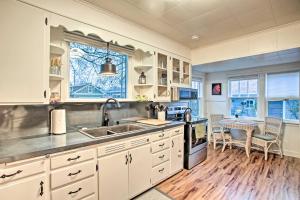 a kitchen with white cabinets and a sink and a table at Whimsical Coeur dAlene Escape, Walk to Beach! in Coeur d'Alene