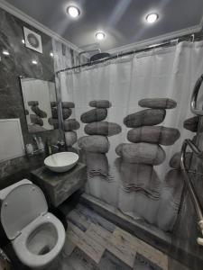 łazienka z zasłoną prysznicową, toaletą i umywalką w obiekcie Люкс академика сатпаева 19 w mieście Pawłodar
