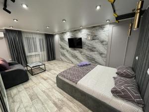 a bedroom with a bed and a tv on a wall at Люкс академика сатпаева 19 in Pavlodar