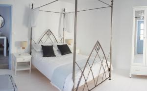 a white bedroom with a canopy bed with black pillows at The Guest House in Skiathos