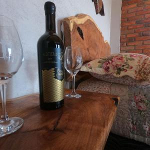 a bottle of wine sitting on a wooden table with two glasses at Hotel Viñedo los Arcángeles in Dolores Hidalgo +13 photos