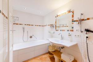 a white bathroom with a tub and a sink at Hotel Engel - Familotel Hochschwarzwald in Todtnauberg