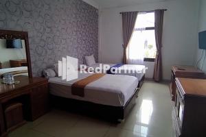 a bedroom with a bed and a desk and a mirror at Hotel Abna Sangatta Mitra RedDoorz in Sengata +44 photos