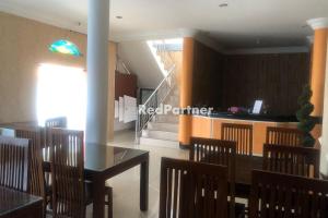 a dining room with a table and chairs and a staircase at Hotel Abna Sangatta Mitra RedDoorz in Sengata