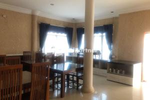 a dining room with a table and chairs and windows at Hotel Abna Sangatta Mitra RedDoorz in Sengata