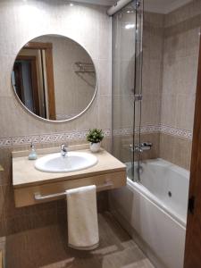 a bathroom with a sink and a tub and a mirror at JARDINES DE VINJOY in Oviedo