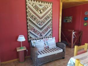 Habitación con silla de mimbre y pared en Mirador de Atuq - Casa Serrana en Villa Yacanto