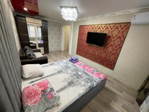 a bedroom with a bed and a tv on the wall at Лермонтова 91 in Pavlodar