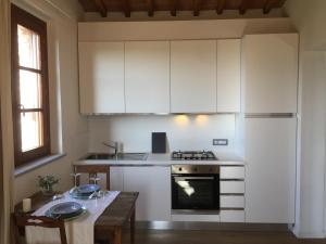 - une cuisine avec des placards blancs, une cuisinière et une table dans l'établissement Oliveta del Verde Appartamento con Grande Giardino 500mt dal Centro, à Sienne