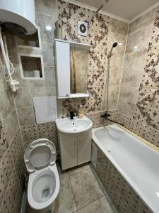 a bathroom with a toilet and a sink and a tub at Лермонтова 91 in Pavlodar