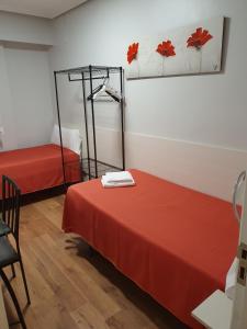 Habitación con 2 camas con sábanas rojas y espejo. en Pensión El Espolón, en Logroño
