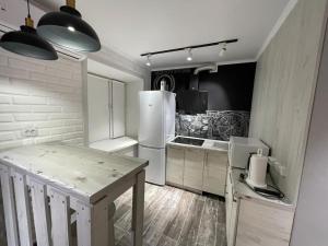 a kitchen with a white refrigerator and a table at ЛЮКС академика сатпаева 47 in Pavlodar
