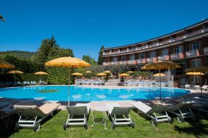 un hotel con una piscina con sillas y sombrillas en Hotel Continental, en Garda