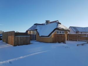 una casa con techo cubierto de nieve en un patio en Fiskerhuset, en Agger