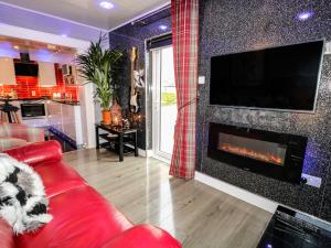 a living room with a red couch and a fireplace at Clubhouse View Apartment in Castlerock
