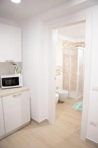 a white kitchen with a microwave and a toilet at B&B da Mamma Anna in Matera