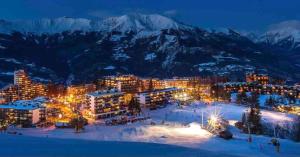 une ville dans la neige la nuit avec des montagnes enneigées dans l'établissement T2 Immeuble Chanteclerc 6 personnes 37m2 PRALOUP 1600, à Uvernet